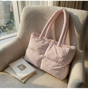 Close-up of pink quilted puffer tote bag with soft nylon texture on a cozy sofa
