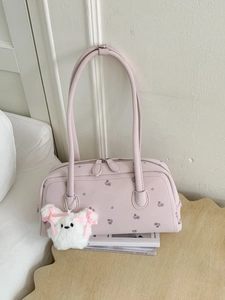Pink floral faux leather tote bag with plush bunny charm on a wooden desk background