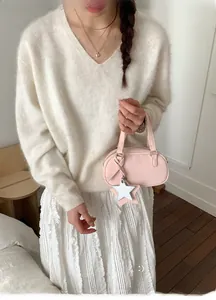 Close-up of pale pink mini bowling bag with star charm styled on a white knit outfit