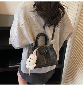 Detail der schwarzen Vintage-Jeans-Eimertasche mit Ledergriffen und weißem Plüschwelpen