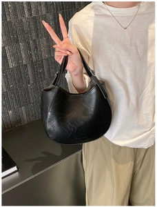 Detail of a black leather hobo bag featuring 'FASHION & BAGS' embossed text