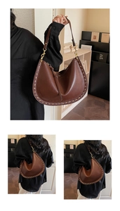 Detail of brown half-moon tote with gold studs, fringe tassel and adjustable strap