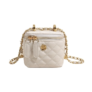 Detail of white quilted mini box bag with gold camellia logo and metal chain strap