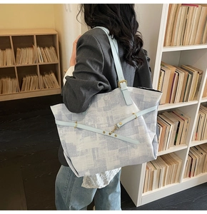 Close-up of a large blue and white geometric tote bag shown on a shoulder