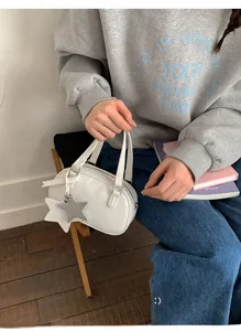 Mini white Boston bag with star charms shown in a casual lifestyle setting