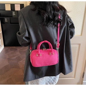 Detailed view of magenta faux suede baguette bag with gold hardware and brand embossing