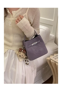 Detail of purple lychee pattern leather bucket bag with silver lock and cute bear charm