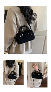 Detail view of black suede mini Boston bag with gold hardware and Rosy Gardenia logo