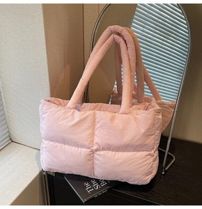 Detailed close-up of pink quilted puffer tote bag on a wooden table with home decor