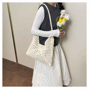 Detail of white crochet knit tote bag showing intricate woven patterns and side tassels