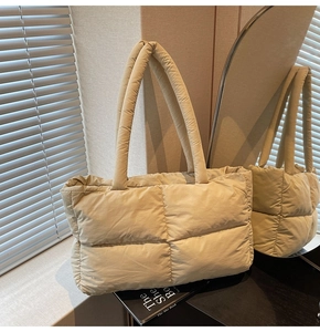 Detail of beige quilted puffer tote bag showing soft nylon texture and padded handles