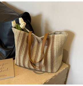 Detailed straw tote bag with brown leather handles and vertical woven texture