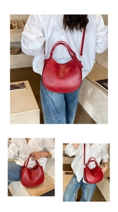 Detail view of red crescent shoulder bag with vintage texture and adjustable strap
