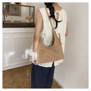 Rear view of model carrying a large woven crochet tote bag with tassel in a cozy room