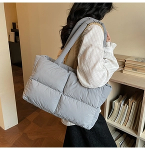 Detailed view of grey quilted puff tote bag worn by model in a minimalist setting