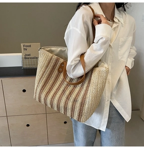 Détail du sac cabas en paille tissé main avec anses en cuir brun et motif rayé
