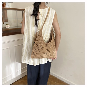 Detail of a brown woven tote bag featuring hollow geometric patterns and a rope shoulder strap