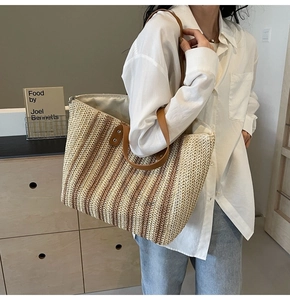 Detail of the woven straw tote bag with striped pattern and premium leather handles