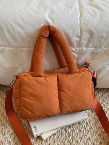 Quilted burnt orange puffer tote bag with thick handles and wide shoulder strap
