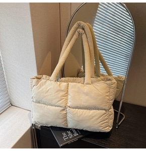 Detail shot of beige quilted puffer tote bag showing soft texture and padded handle
