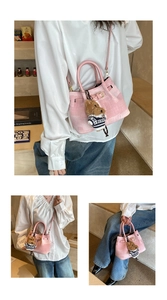 Detail der rosa karierten Eimertasche mit Plüschbären-Anhänger und Schultergurt