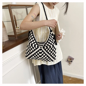 Detail of hand-woven black and white heart pattern hobo bag with tassel accent