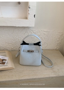 Detail of light blue mini bucket bag with leather texture, top handle and crossbody strap