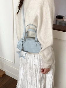 Light blue shell bowling bag with star charm shown on a model in a minimalist setting