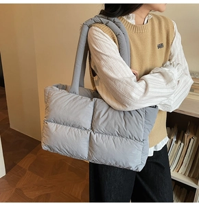 Close-up of a grey quilted puffer tote bag with thick padded handles for winter style