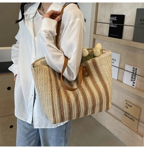 Detailed view of striped straw tote bag featuring brown leather handles and woven texture