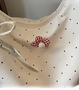 Detail of beige canvas tote with black polka dots and red gingham fabric flower charm