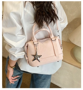 Pink Boston handbag detail featuring a star pendant and metallic silver hardware accents
