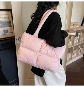 Pink quilted puffer tote bag shown on shoulder in a stylish home office setting