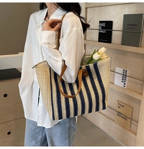 Détail d'un sac cabas en paille tressée à rayures bleues et lanières en cuir marron