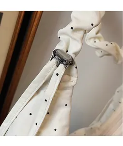 Detail of silver square metal buckle and ruched strap on polka dot shoulder bag