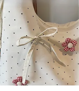 Close-up of white canvas tote bag with black dots and decorative red floral fabric patches