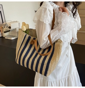 Detail of blue striped straw tote bag with brown leather straps in a lifestyle setting