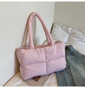 Pink quilted puff tote bag with soft padded handles styled on a bed with denim jacket