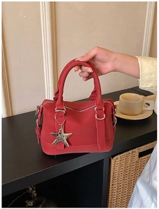 Detail of red matte leather Boston bag with iconic silver star pendant and sturdy handles