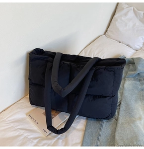 Detail view of a large black quilted puffer tote bag with soft padded shoulder straps
