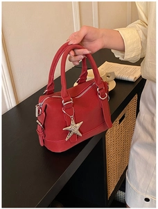 Detailed view of red leather bowling bag with silver star pendant and top zip closure