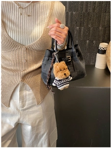 Detail der dunklen Denim Mini Eimertasche mit braunem Plüschhund Anhänger und Ledergriffen