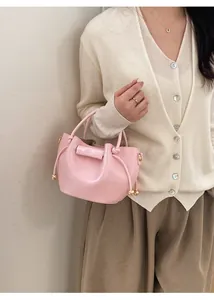 Details einer rosa Beuteltasche mit Kordelzug und goldenen Perlen am modischen Outfit