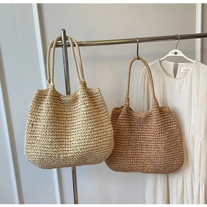Dettaglio di borse tote in paglia intrecciata in beige e marrone su un gancio