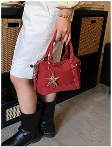 Close-up of a red leather bowling bag with star charm and top handles held by a model