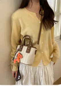Mini woven tote bag with brown leather trim and cute horse charm on a female model