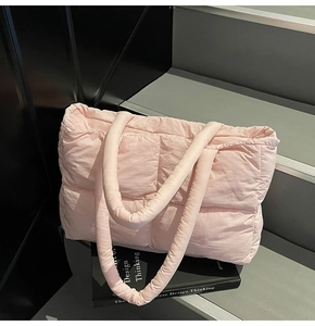 Detailed view of pink quilted puffer tote bag on a modern architectural setting