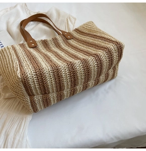 Macro shot of striped straw tote bag showing tight weave texture and brown leather straps