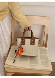 Detail of contrast stitch bucket bag with brown leather trim and orange horse charm