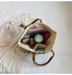 Top view of spacious straw tote interior holding a tablet, water bottle, and wallet